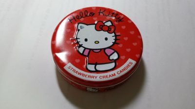 En röd godisask med Hello Kitty på som vinkar med ena tassen.