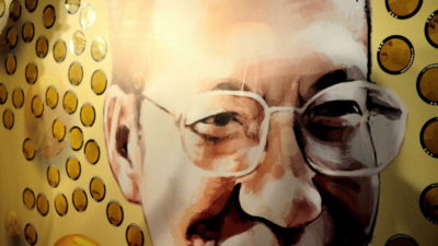 Liu Xiaobo ler ett snett leende och hans glasögon utan bågar lyser i det starka ljuset från sidan.