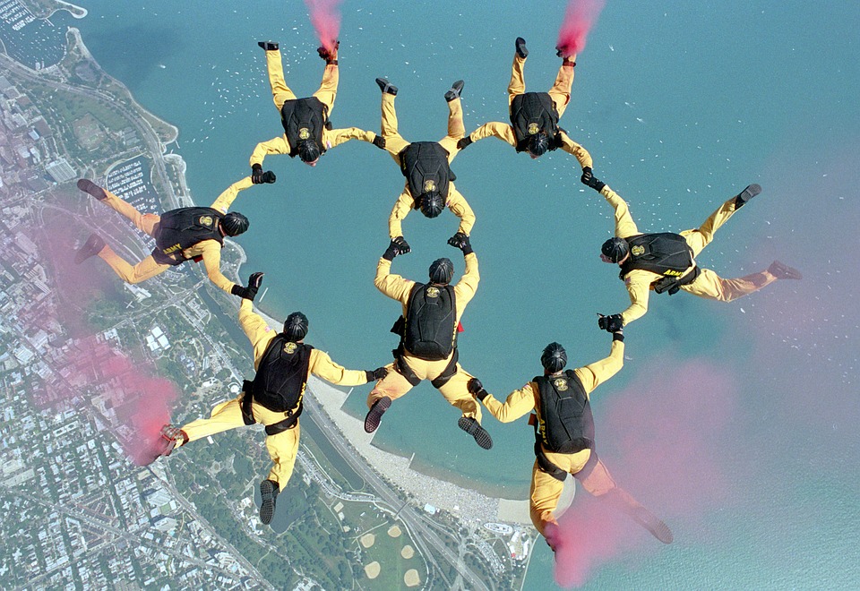 Åtta fallskärmshoppare gör en formation i luften som ser ut som två ringar som går in i varnadra.