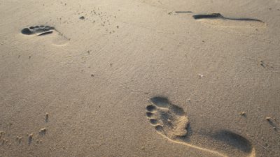 Två fotspår i sand.