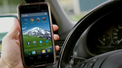 En hand håller en mobil inne i en bil.