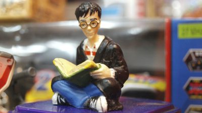 En liten leksaksfigur föreställer Harry Potter som sitter ner med en bok i famnen.