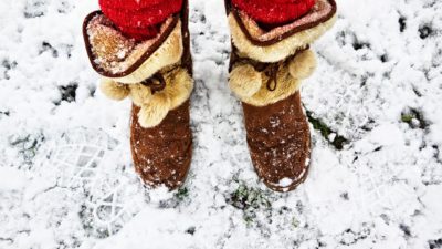 En person med bruna fluffiga vinterskor står i snö