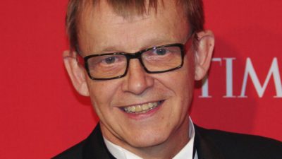 Hans Rosling tittar in i kameran. Han ser ut att vara i övre medelåldern. Han har kavaj och fluga på sig. Han har glasögon och ganska tunt kort hår som ligger kammat framåt. Hans tänder är gula och han har ganska stora öron.