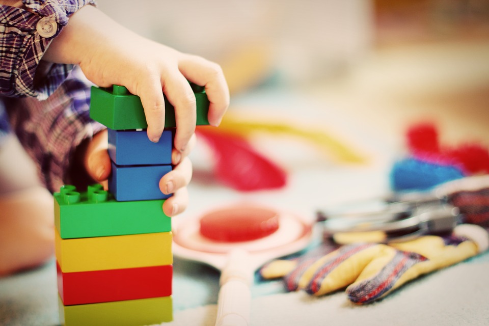 Ett barn som leker med klossar med andra leksaker i bakgrunden