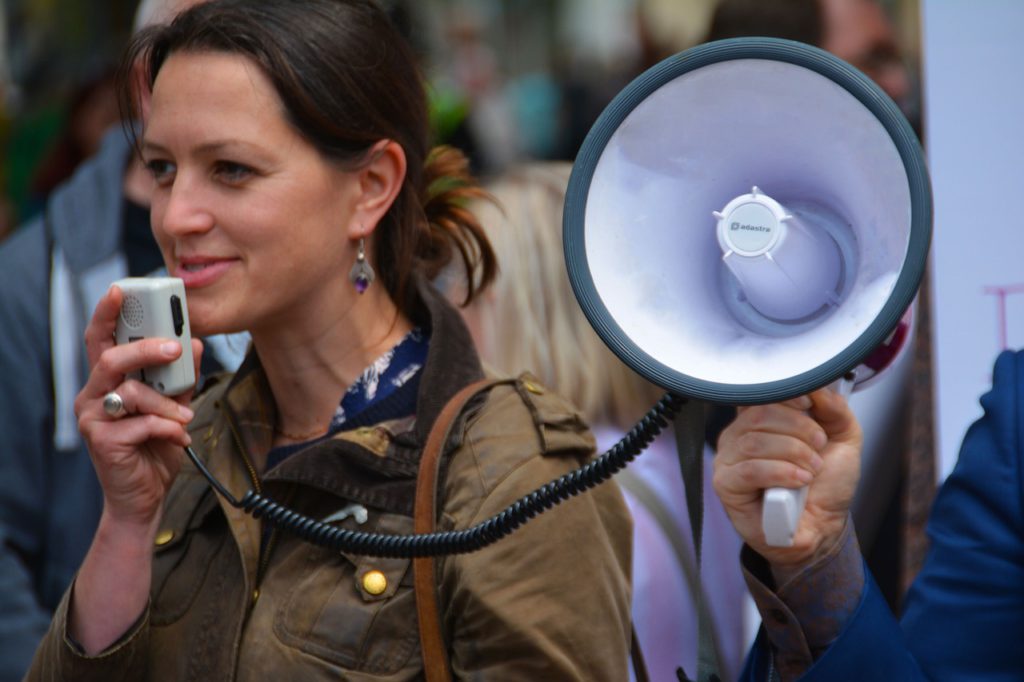 En kvinna talar i en megafon under en demonstration.