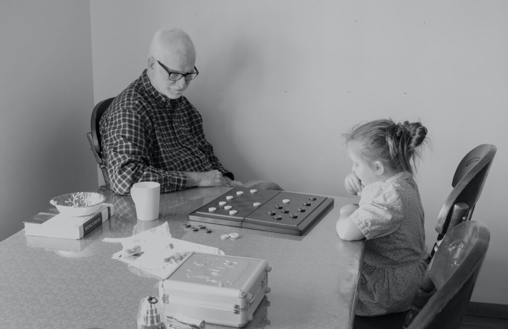 En äldre man och en flicka spelar spel