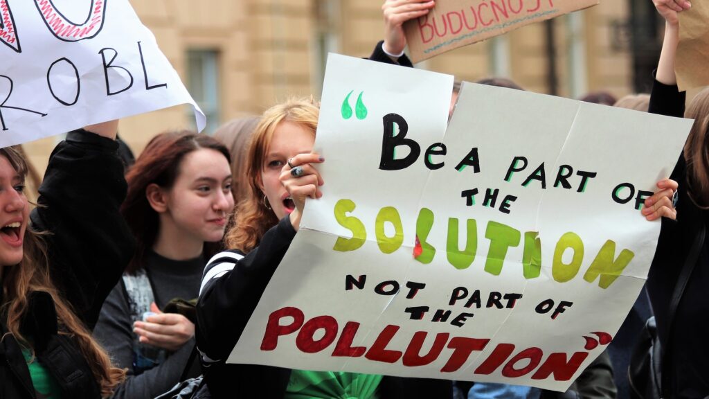 En tjej protesterar mot klimatförändringarna. Hon håller i ett plakat med texten "Be a part of the solution, not a part of the pollution".