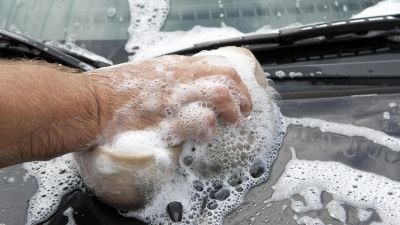 Närbild på någon som skrubbar en bil ren.